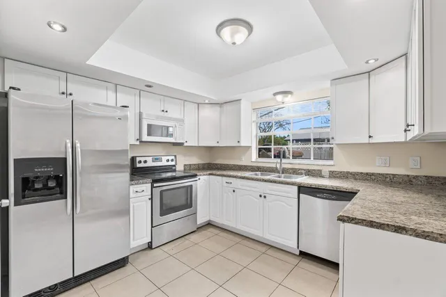 a kitchen with granite countertop white cabinets and white stainless steel appliances