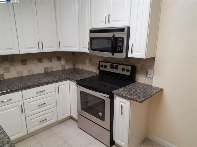 a kitchen with granite countertop white cabinets stainless steel appliances and a sink