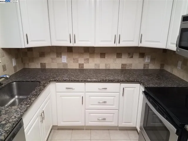 a kitchen with granite countertop white cabinets and a stove
