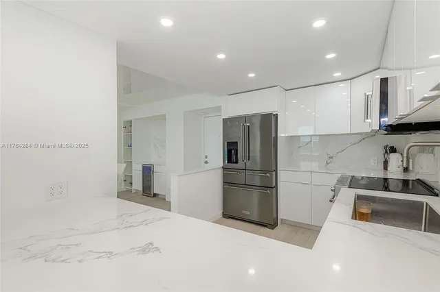 a view of kitchen with stainless steel appliances granite countertop white cabinets and window