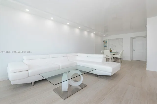 a living room with couches and kitchen view with wooden floor