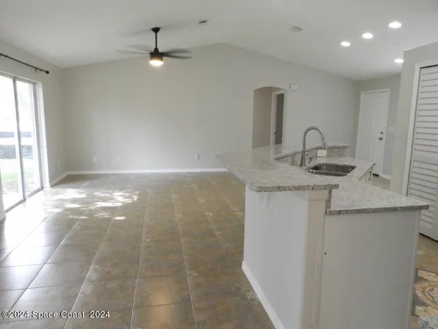 a kitchen with kitchen island granite countertop a sink and a stove top oven