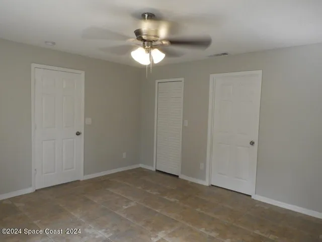 a view of an empty room with a chandelier fan