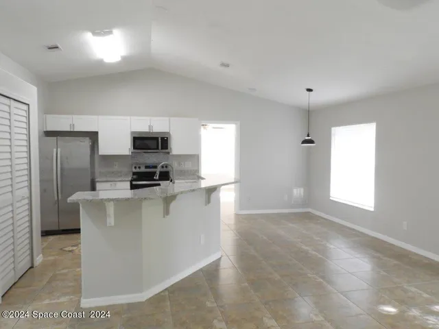 a kitchen with stainless steel appliances a microwave a sink a refrigerator and window