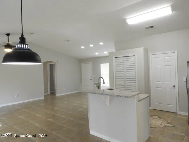 a kitchen with kitchen island granite countertop a sink and a refrigerator