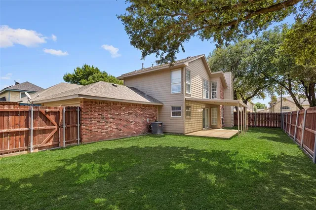 a view of a yard with a house and a large tree with wooden fence
