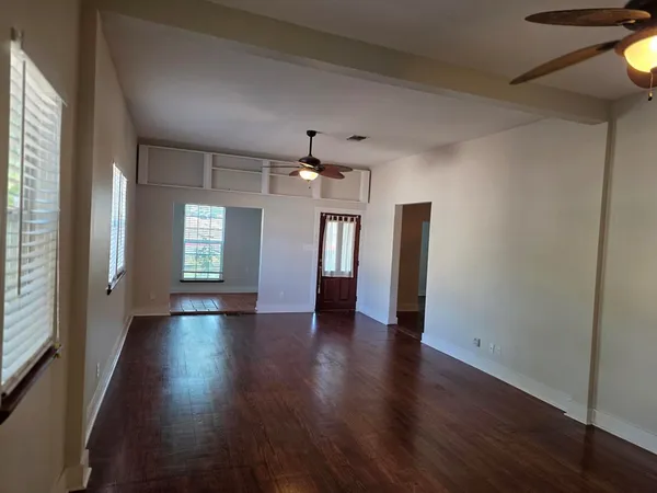 a view of an empty room with wooden floor and a window