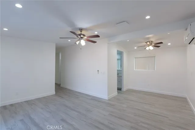 an empty room with wooden floor and fan