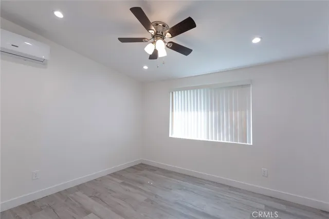 an empty room with wooden floor and chandelier fan