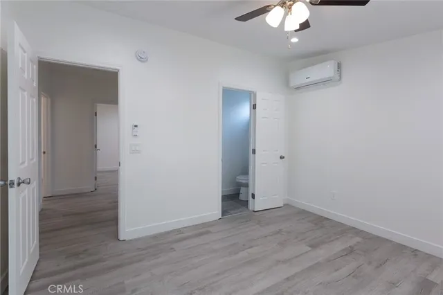 a view of an empty room with window and chandelier fan
