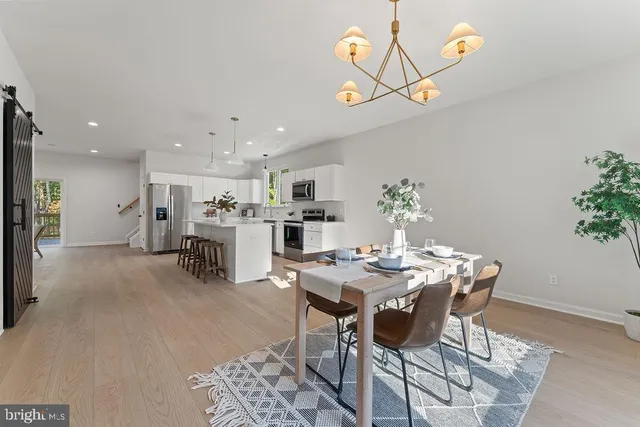 a kitchen with stainless steel appliances a refrigerator a stove a sink a dining table and chairs with wooden floor