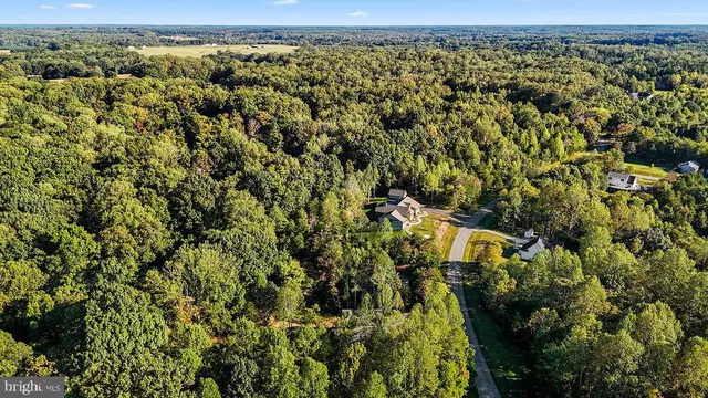 an aerial view of residential house with outdoor space and trees all around