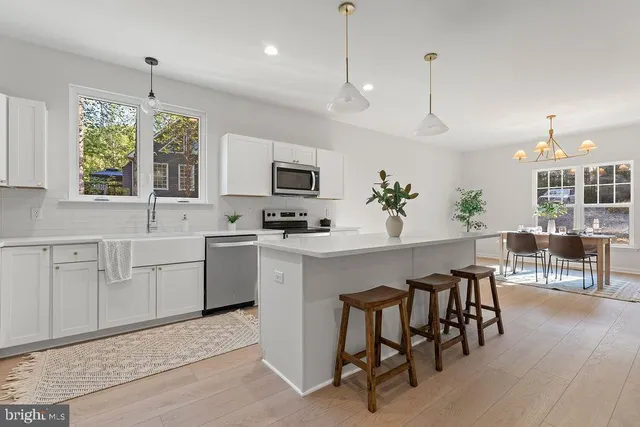 a kitchen with stainless steel appliances a table chairs refrigerator and sink