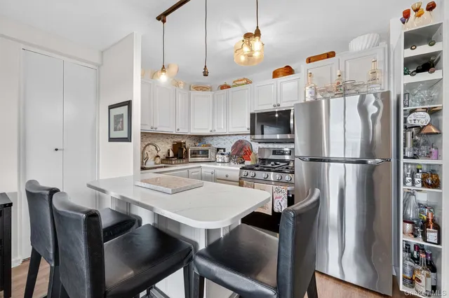 a kitchen with a refrigerator a stove and white cabinets