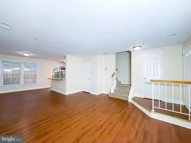 a view of empty room with wooden floor and windows