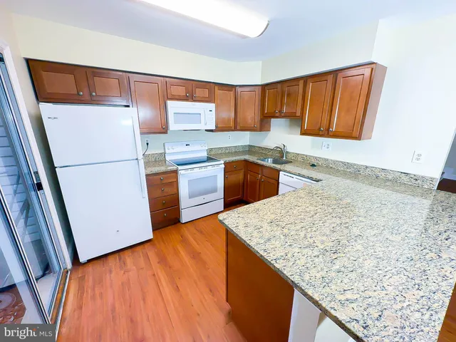 a kitchen with granite countertop wooden cabinets and white appliances