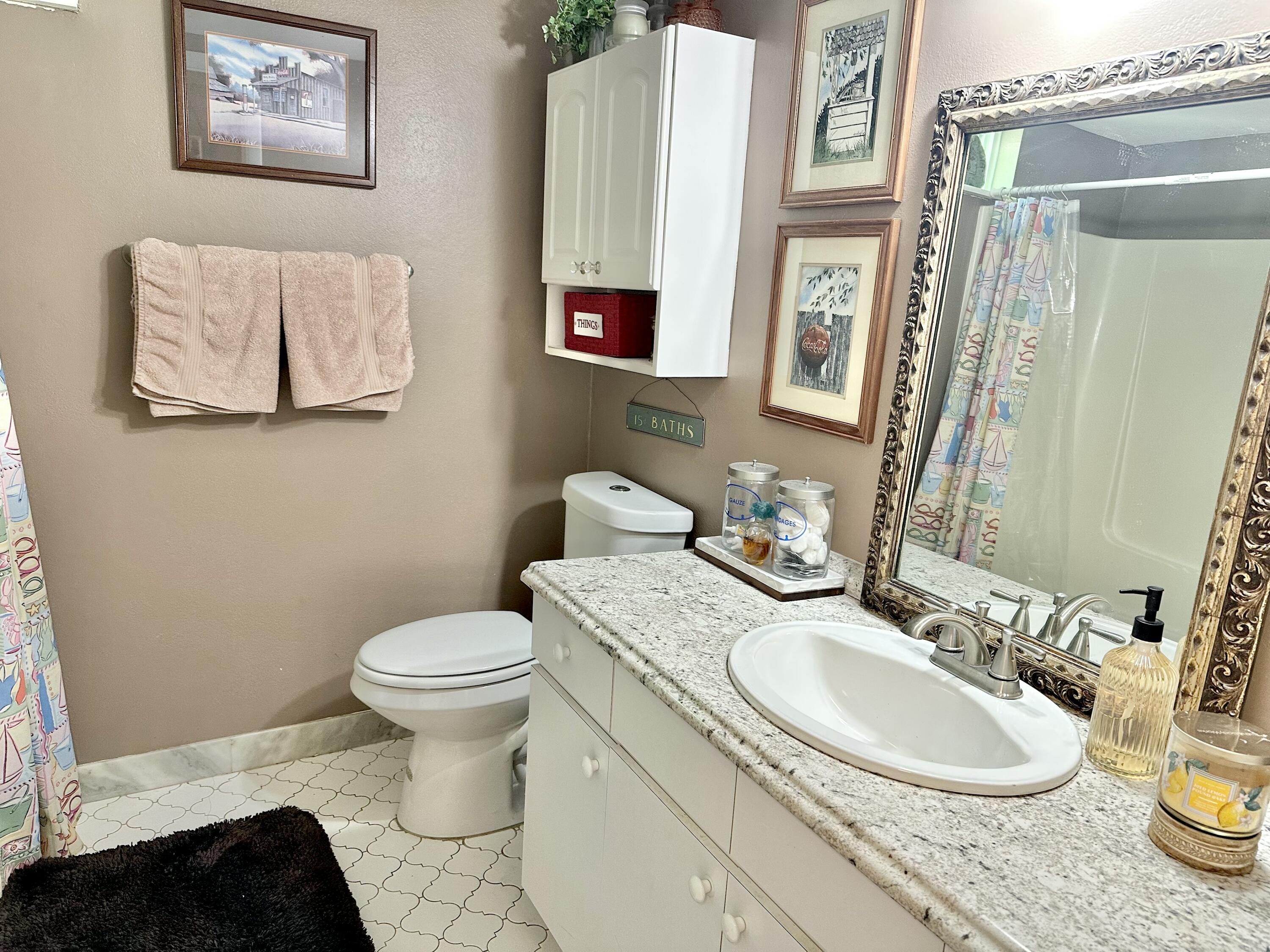 10821 North Military Trail, Unit 21 Palm Beach Gardens, FL 33410 - Photo 27 of 34 a bathroom with a granite countertop toilet sink and mirror