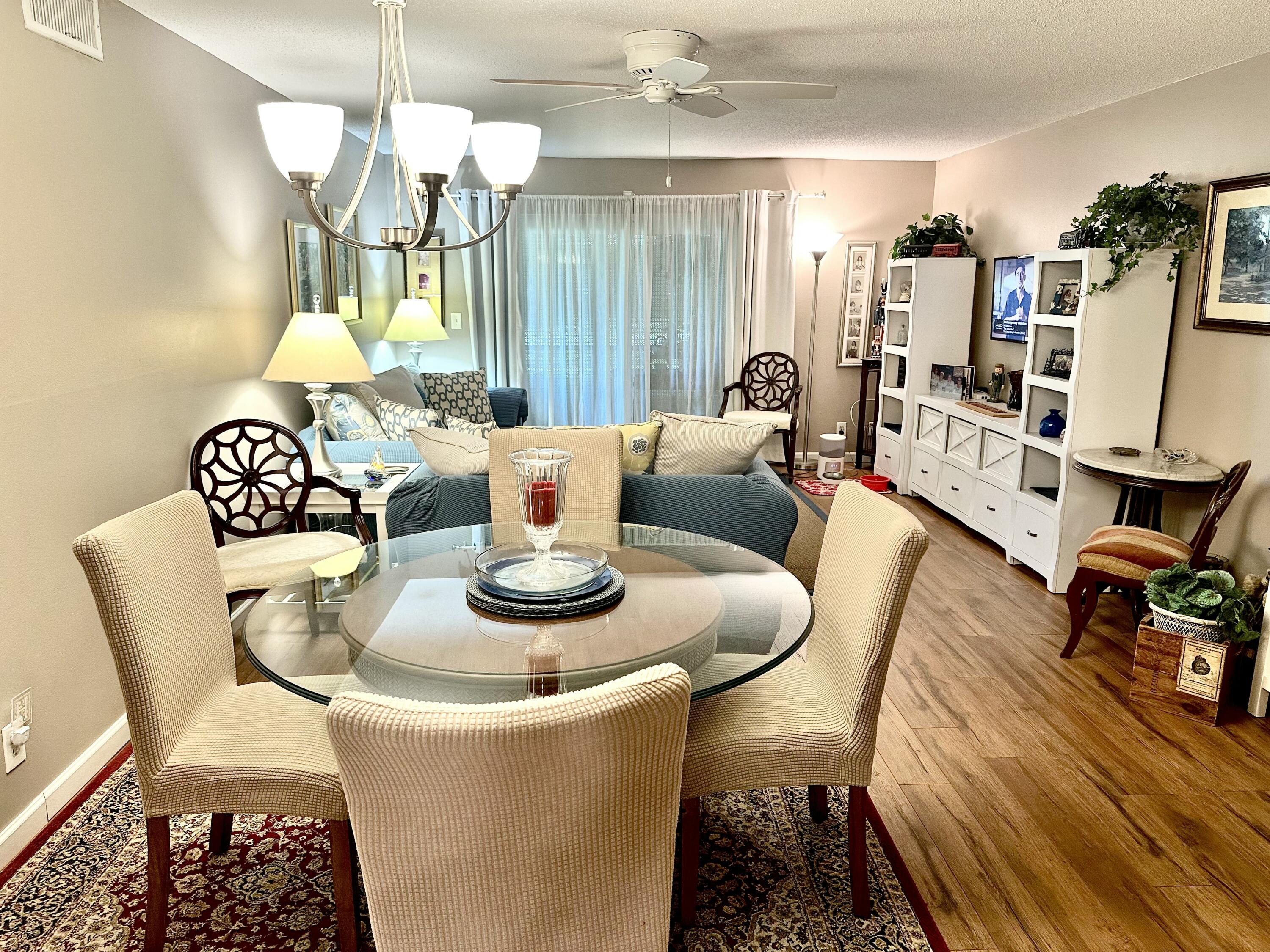 10821 North Military Trail, Unit 21 Palm Beach Gardens, FL 33410 - Photo 5 of 34 a dining room with furniture a chandelier and wooden floor