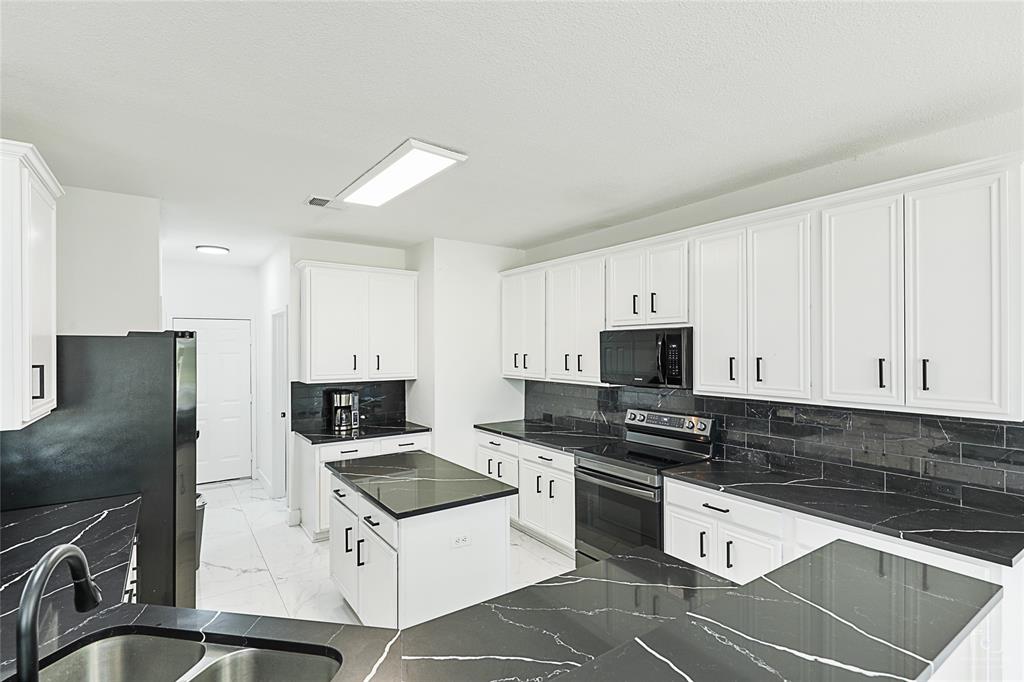 3805 Overlook Court The Colony, TX 75056 - Photo 6 of 29 a kitchen with granite countertop a stove sink and refrigerator