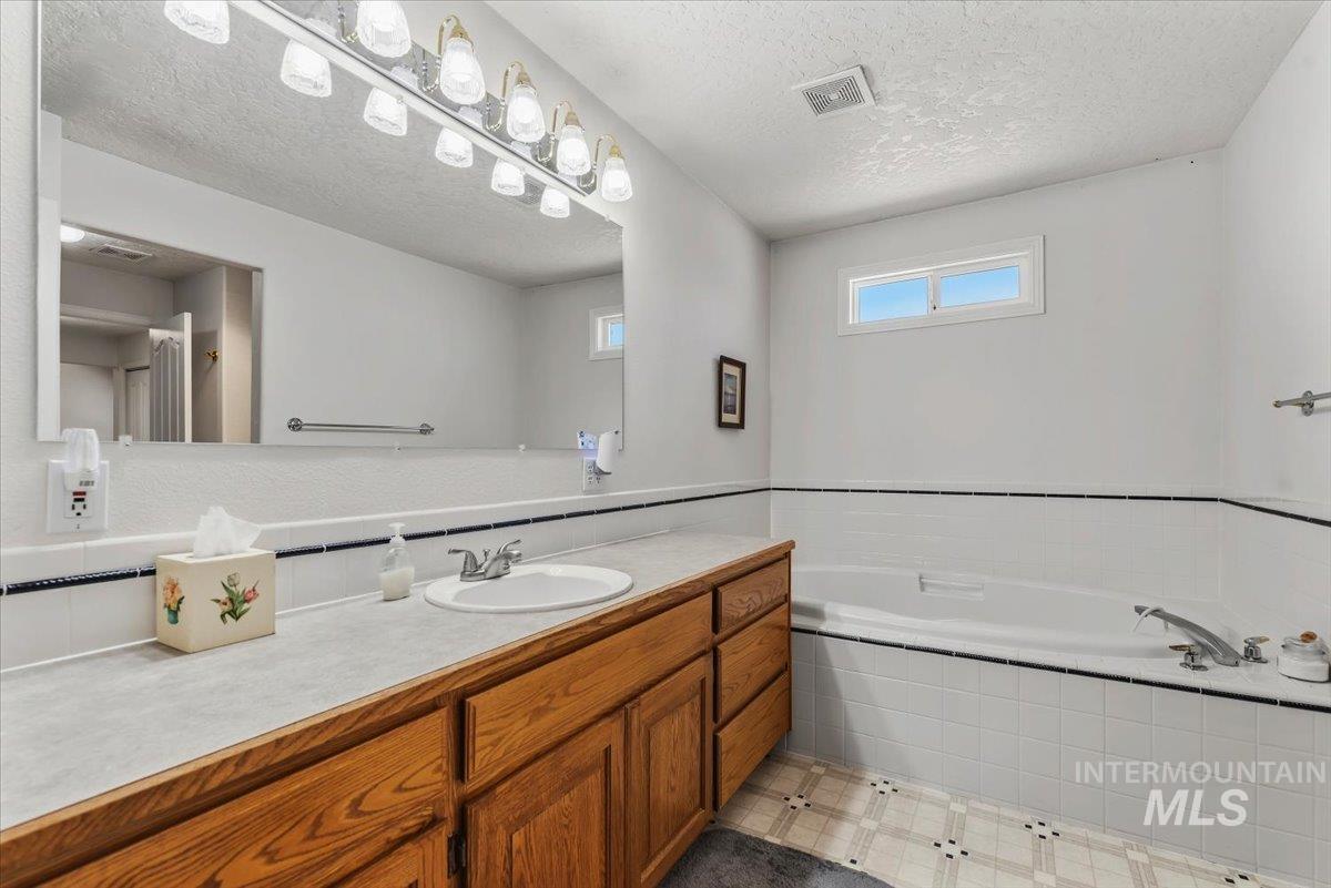 2331 Gulley Road Homedale, ID 83628 - Photo 20 of 46 Bathroom featuring a wood-finish vanity with an integrated sink, a large wall mirror, and a wall-mounted light fixture