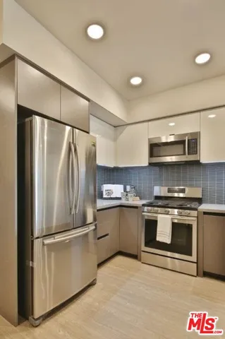 a kitchen with stainless steel appliances granite countertop a refrigerator and a stove top oven