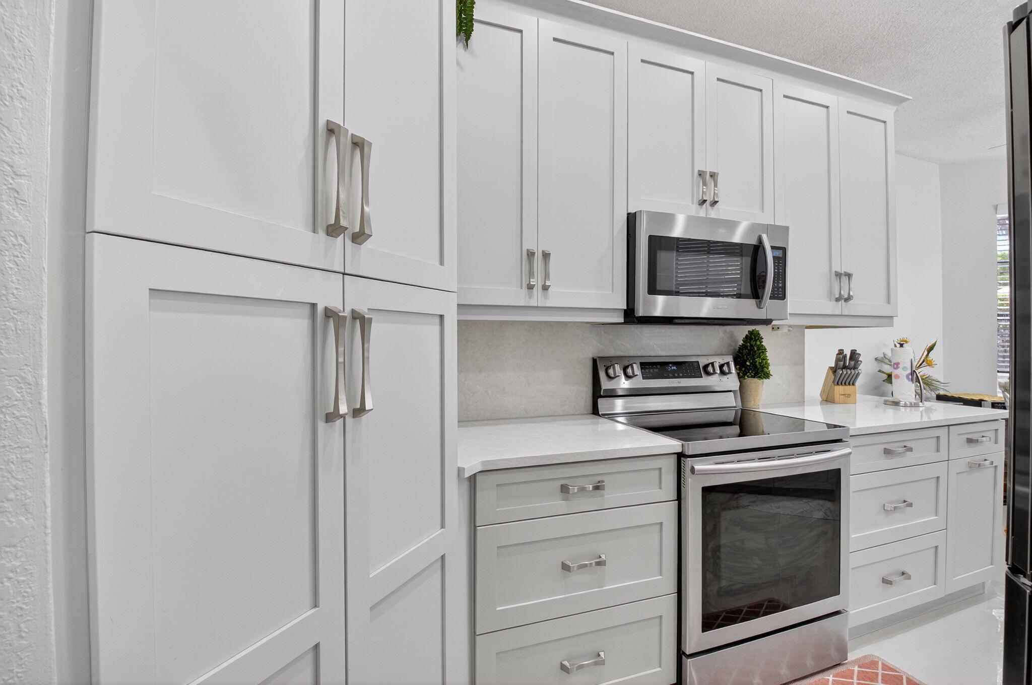 2423 Northwest 63rd Street Boca Raton, FL 33496 - Photo 13 of 83 a kitchen with stainless steel appliances white cabinets and a stove top oven