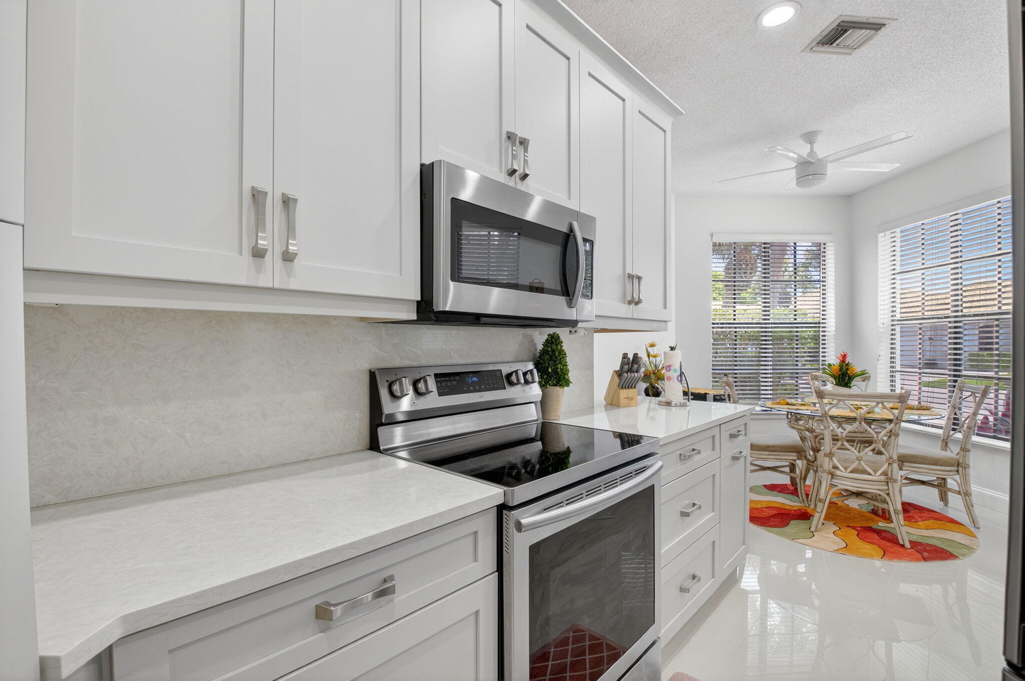 2423 Northwest 63rd Street Boca Raton, FL 33496 - Photo 14 of 83 a kitchen with stainless steel appliances granite countertop a stove and white cabinets