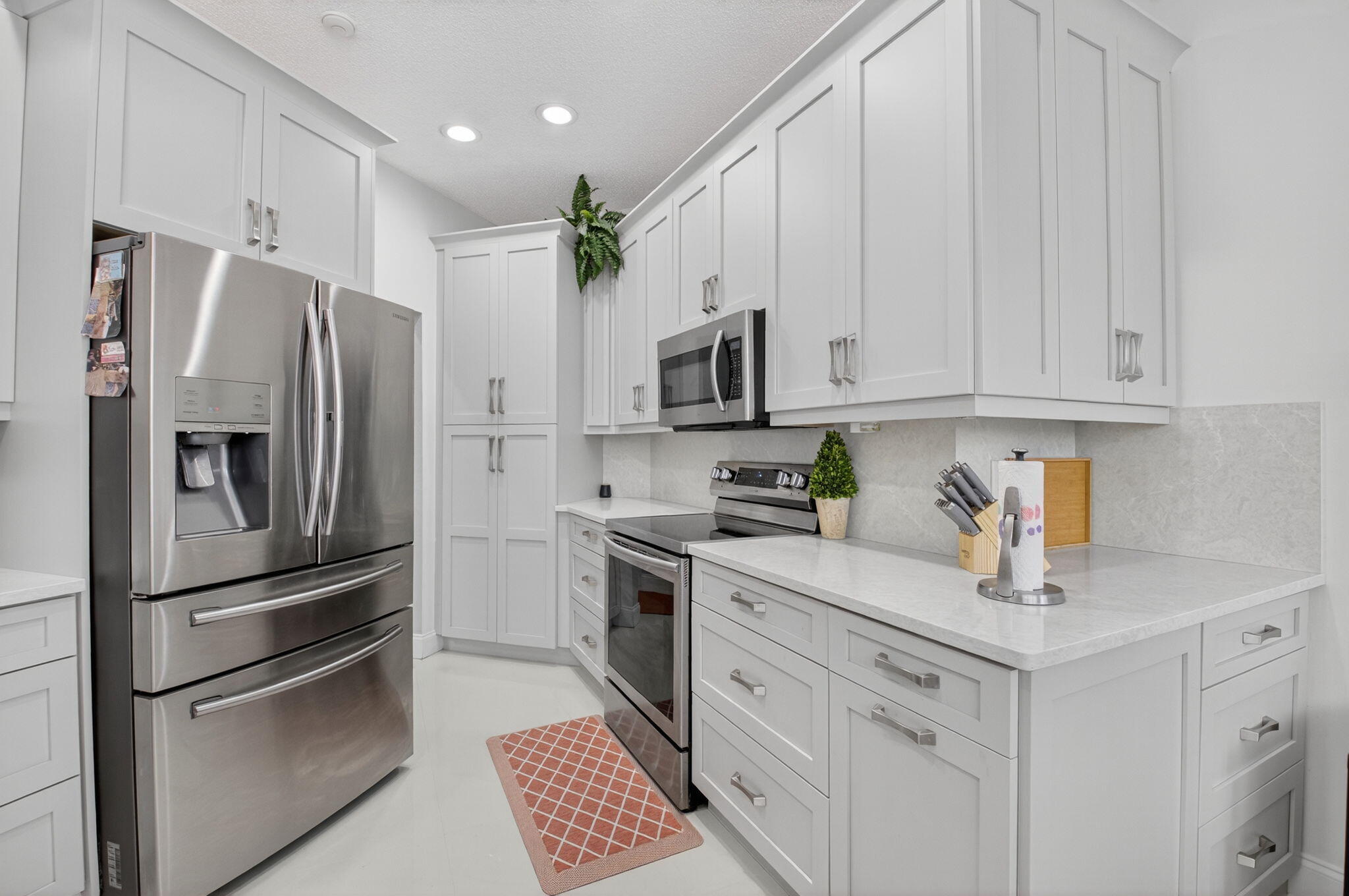 2423 Northwest 63rd Street Boca Raton, FL 33496 - Photo 16 of 83 a kitchen with white cabinets and stainless steel appliances