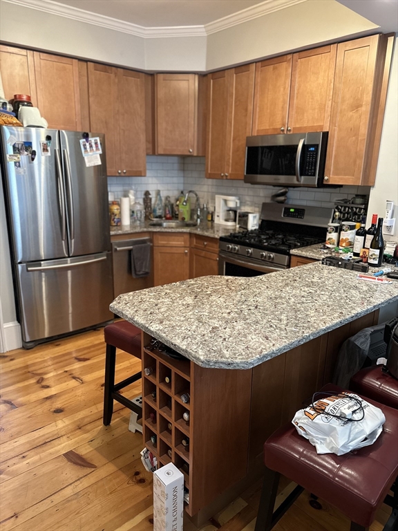 61 Putnam Street, Unit 2 Boston, MA 02128 - Photo 5 of 11 a kitchen with stainless steel appliances granite countertop a stove top oven a refrigerator a sink and a dining table with wooden floor