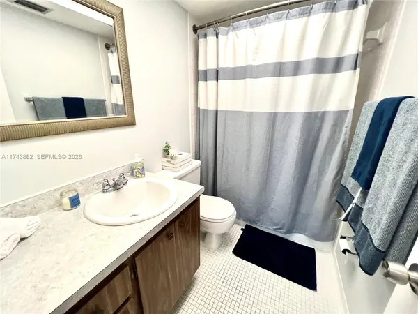a bathroom with a sink a toilet a mirror and shower curtain