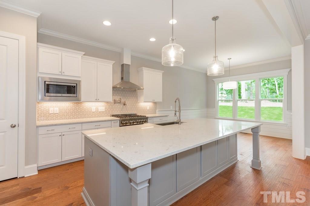 8000 Ghost Pony Trail Raleigh, NC 27613 - Photo 8 of 30 a kitchen with a stove a sink a center island and a wooden floor