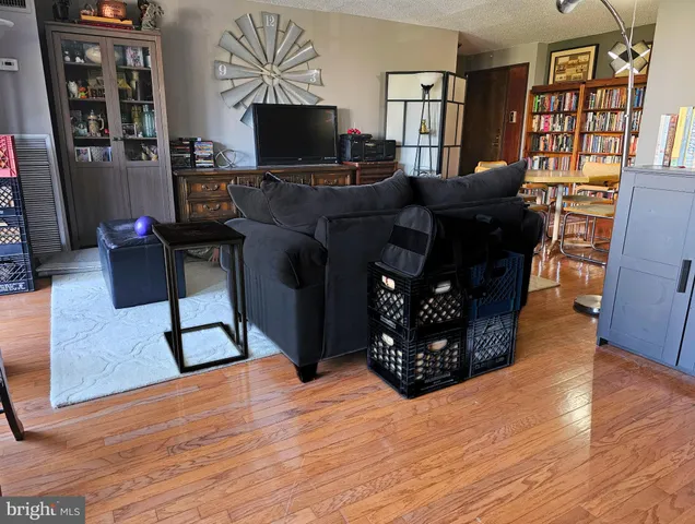 a living room with furniture a flat screen tv and a refrigerator