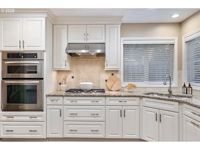 a kitchen with granite countertop white cabinets and stainless steel appliances