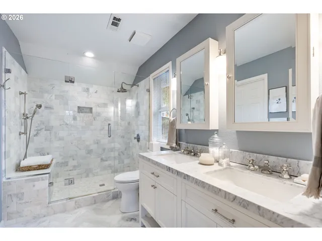 a bathroom with a granite countertop bathtub shower sink mirror and toilet