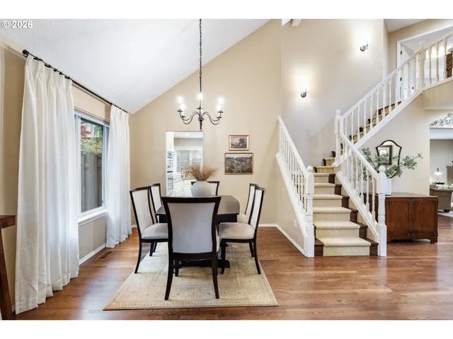 a dining room with wooden floor a chandelier a wooden table and chairs