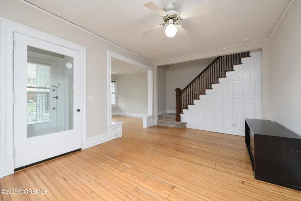 a view of an empty room with wooden floor and a chandelier