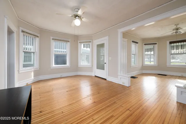 a view of empty room with wooden floor and fan