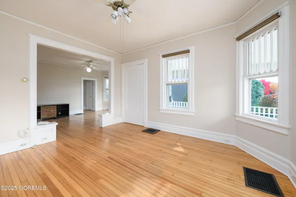 a view of an empty room with wooden floor and a window