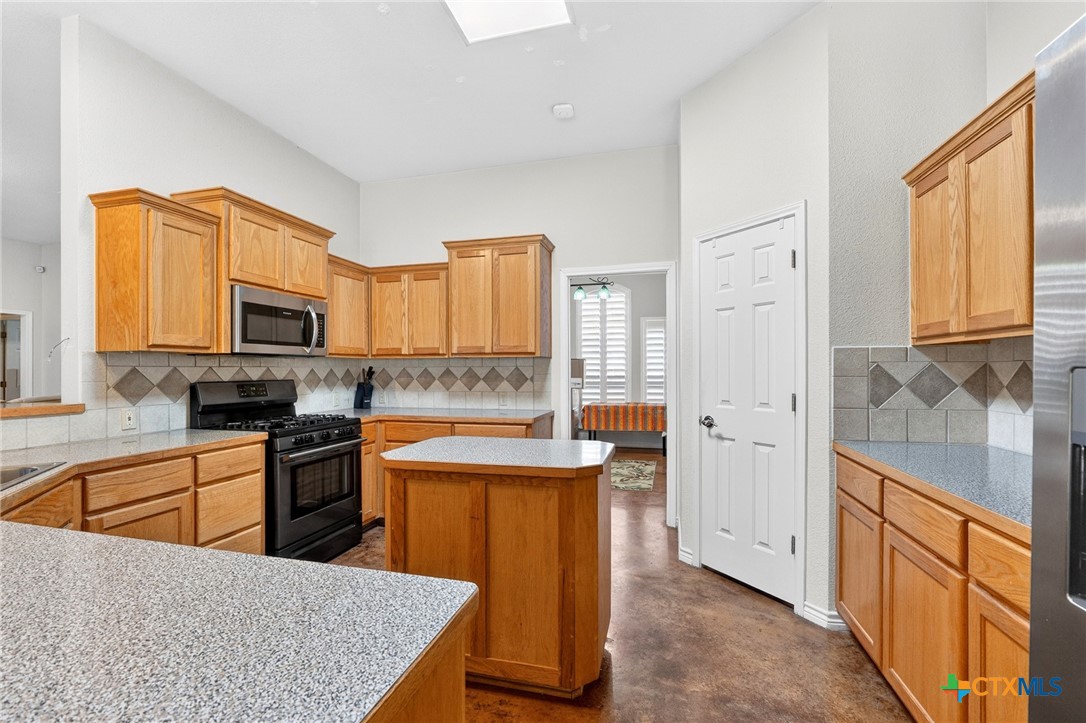 421 Sunset Ridge Drive Killeen, TX 76549 - Photo 23 of 47 a kitchen with stainless steel appliances granite countertop a stove top oven a sink a refrigerator and white cabinets with wooden floor