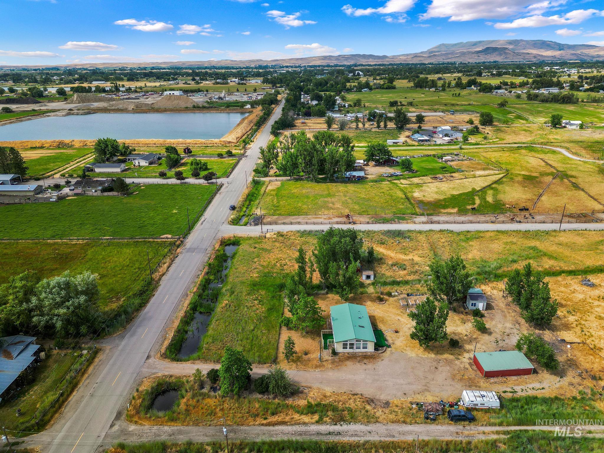 3680 South Mill Road Emmett, ID 83617 - Photo 34 of 38 Expansive rural property featuring a single-story residence with a green metal roof, multiple outbuildings, and mature trees