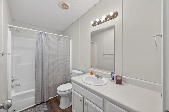 a bathroom with a granite countertop sink toilet a shower and a mirror