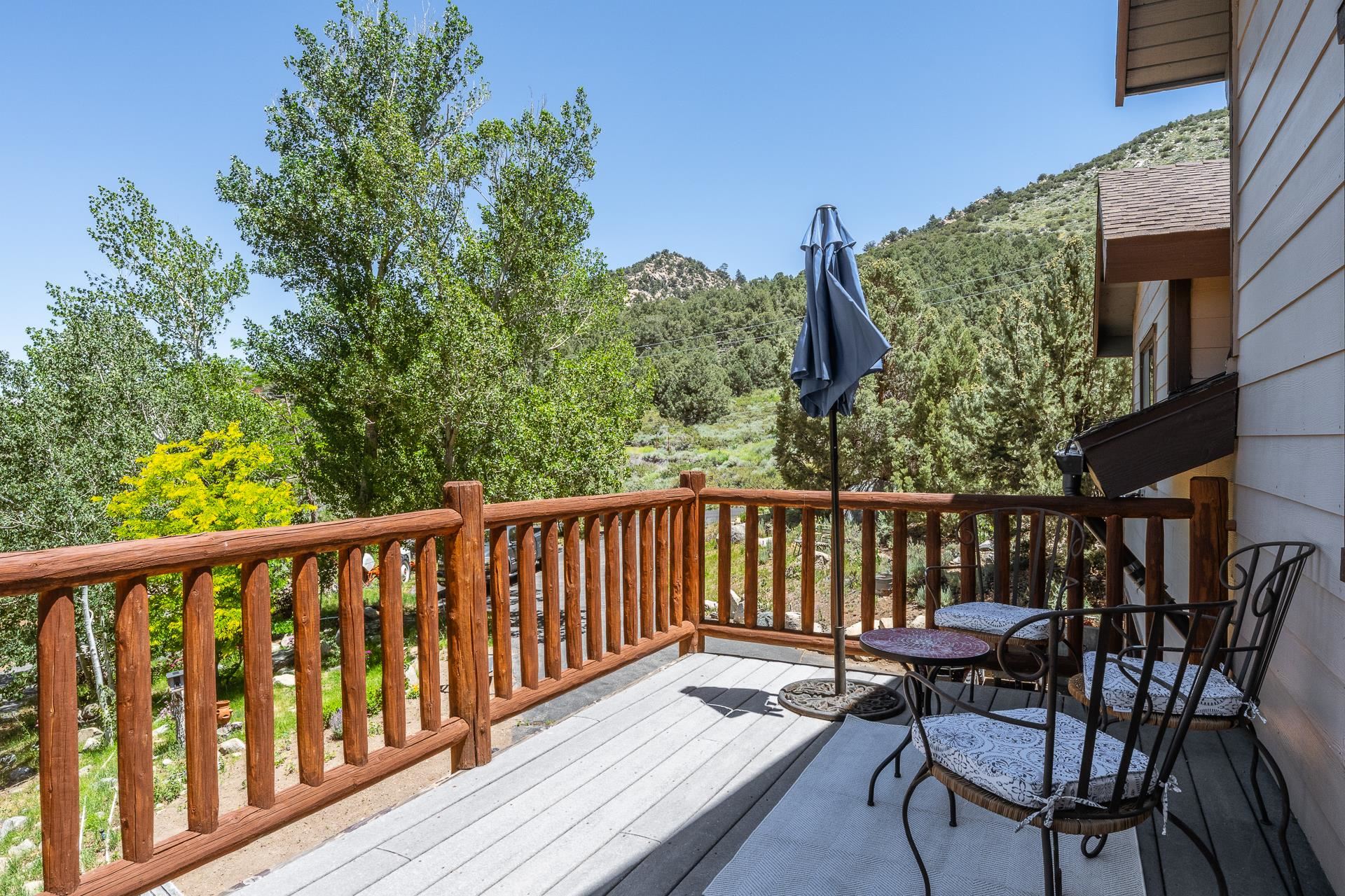 537 Aspen Spring Ranch Road Mammoth Lakes, CA 93546 - Photo 10 of 40 Expansive outdoor deck featuring wood-finish railing, composite decking, and a backdrop of mature trees and distant hills