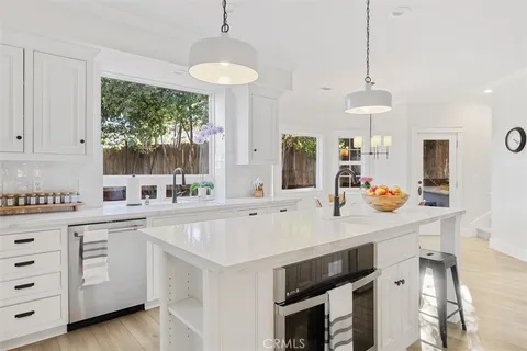 a kitchen with a stove a sink a center island and windows