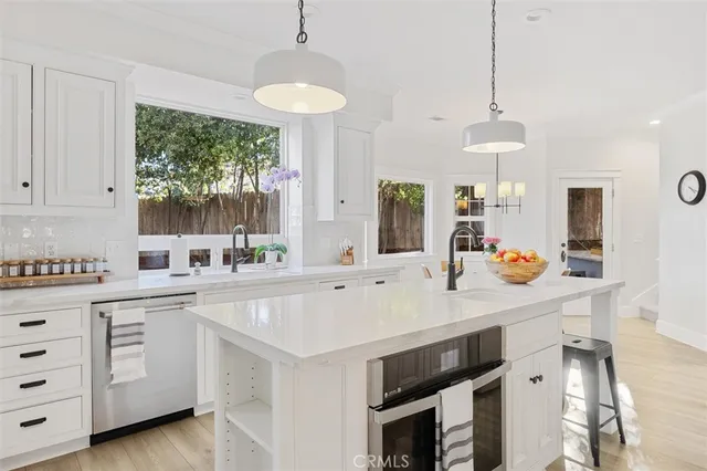 a kitchen with a stove a sink a center island and windows