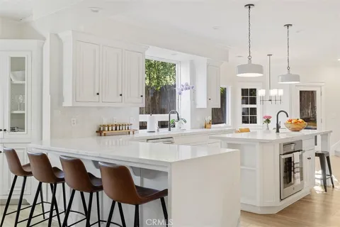 a kitchen with stainless steel appliances granite countertop a table chairs and white cabinets