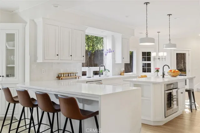 a kitchen with stainless steel appliances granite countertop a table chairs and white cabinets