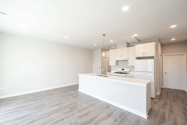 a large white kitchen with kitchen island a sink a stove and a refrigerator