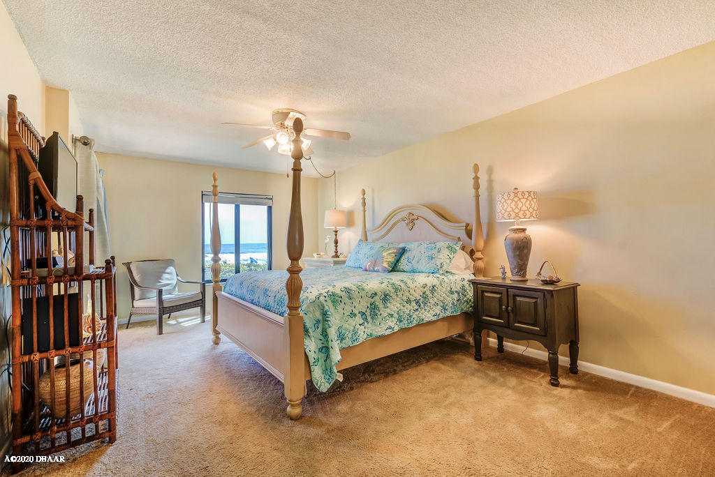 1275 Ocean Shore Boulevard, Unit 108 Ormond Beach, FL 32176 - Photo 15 of 26 a bedroom with a bed next to a window and a flat screen tv