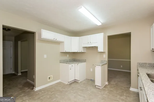 a kitchen with white cabinets and refrigerator