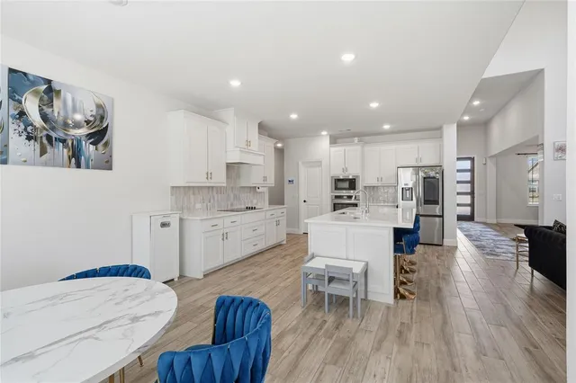 a kitchen with granite countertop a table chairs a sink dishwasher stove and cabinets with wooden floor